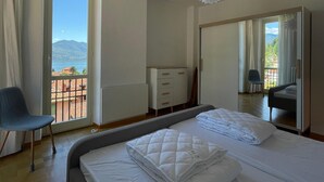 A bedroom with a bed, a chair, a dresser, and a large mirror.