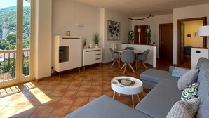 A modern living room with a sofa, a dining table with chairs, and a kitchen area with cabinets and a countertop.