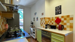 A compact kitchen with a gas stove, oven, and a coffee maker on the counter.