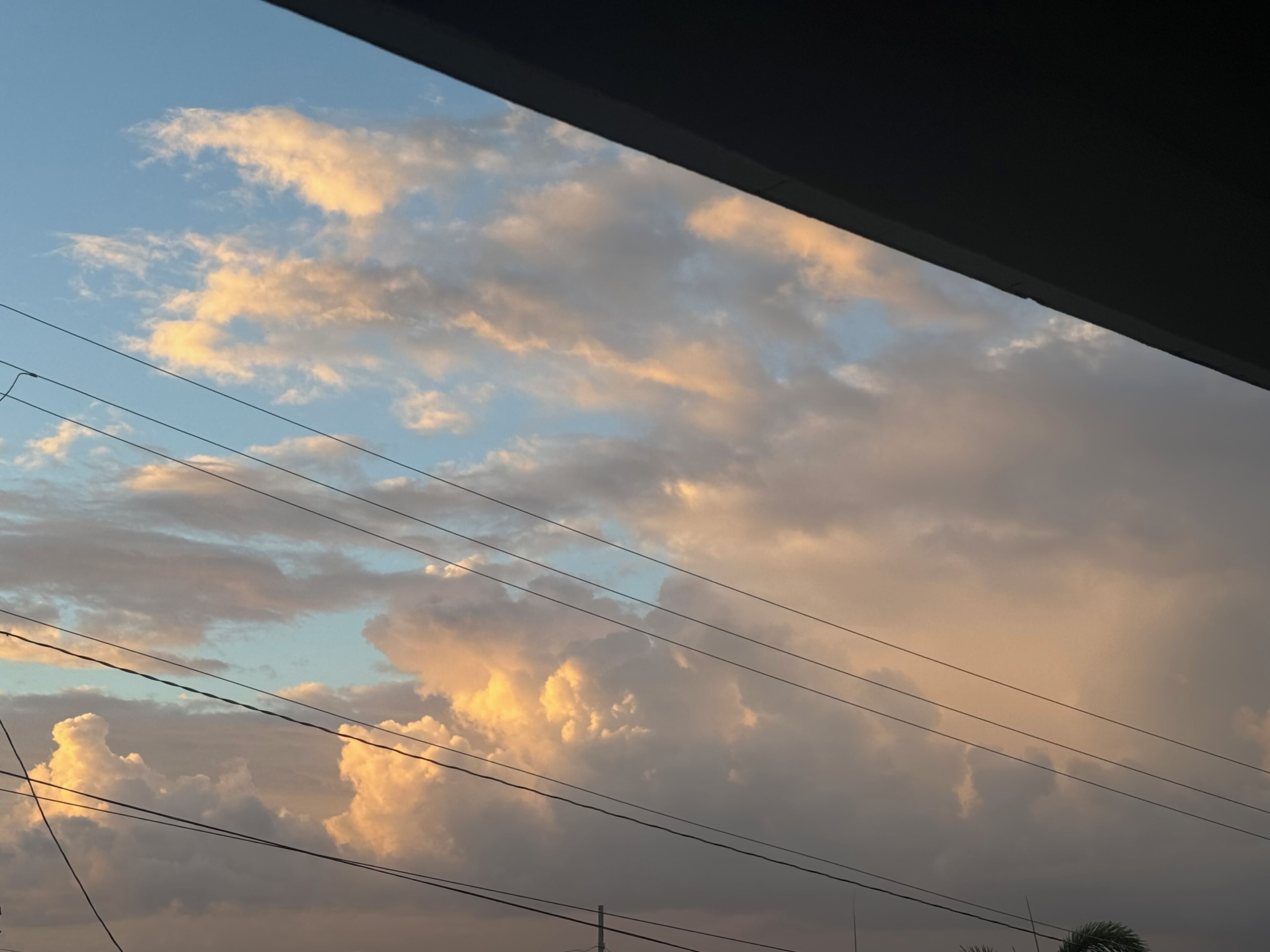 Een uitzicht op de lucht met wolken en hoogspanningslijnen.