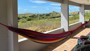 A room with a hammock, large windows, and a view of a hilly landscape. - Sunsets, Breezes & Caribbean Views • Private Puerto Rico Getaway (Salinas)