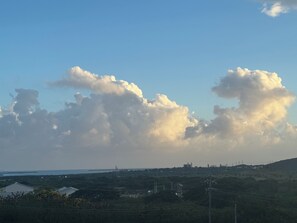 A landscape with a clear sky and large clouds. There are buildings and power lines in the foreground.