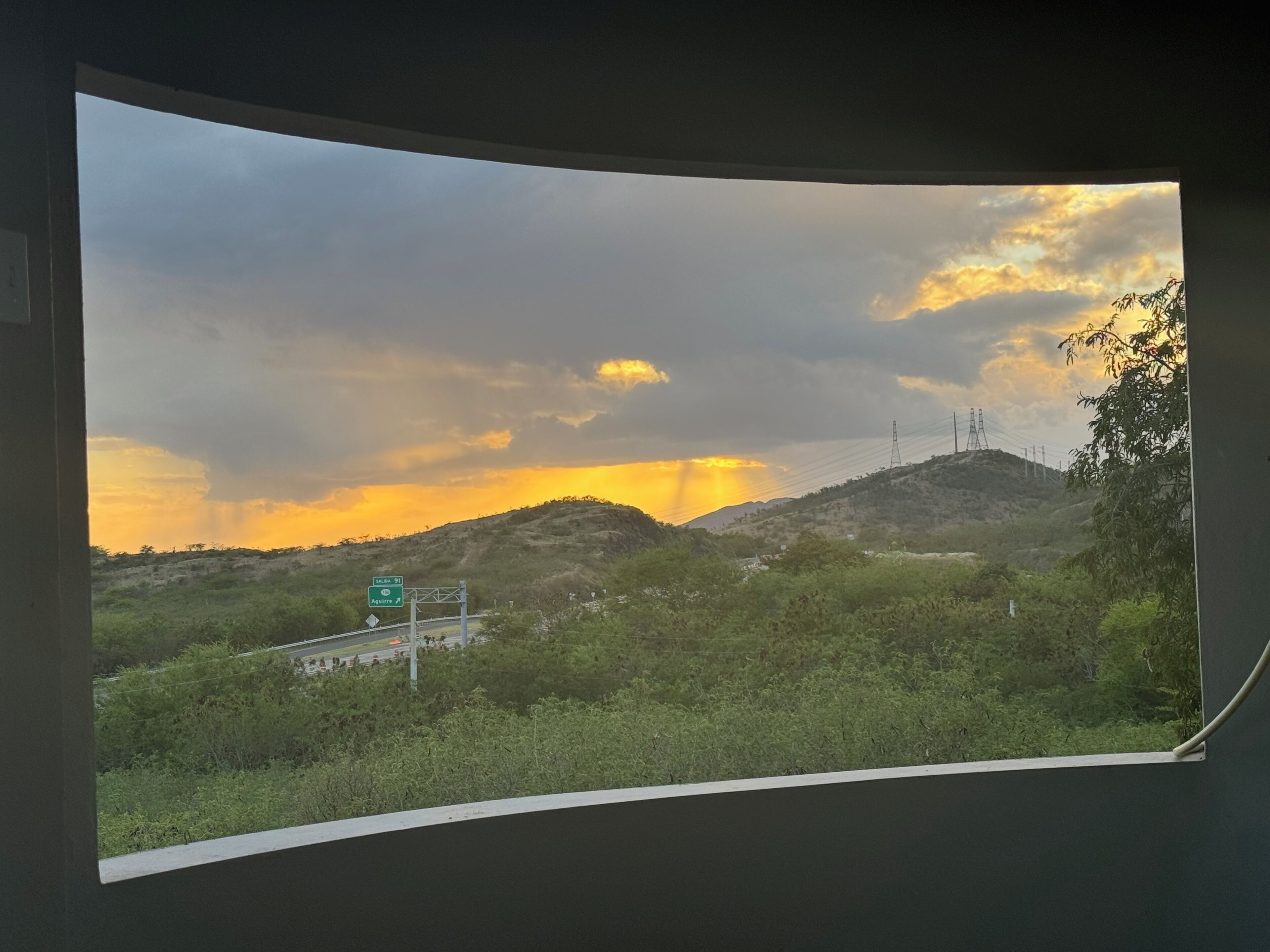 A view from a window overlooking a landscape with hills, a road, and a sign for 'Salina St' and 'Aguirre'.