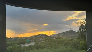 A view from a window overlooking a landscape with hills, a road, and a sign for 'Salina St' and 'Aguirre'. - Sunsets, Breezes & Caribbean Views • Private Puerto Rico Getaway (Salinas)