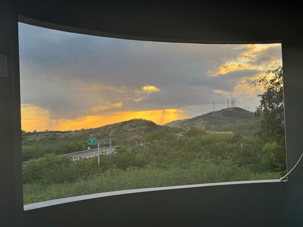 A view from a window overlooking a landscape with hills, a road, and a sign for 'Salina St' and 'Aguirre'.