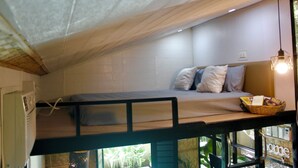 Un lit superposé avec un matelas, des oreillers et un panier rempli d’objets sur le lit supérieur.