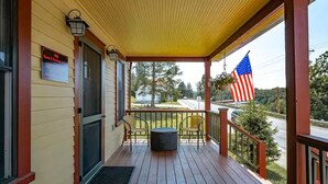 A covered porch with a wooden floor, two chairs, a small round table, and an American flag. - Historic Sears Roebuck House (Thomas)