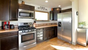 A modern kitchen with dark wood cabinets, stainless steel appliances, and a window providing natural light. - Historic Sears Roebuck House (Thomas)