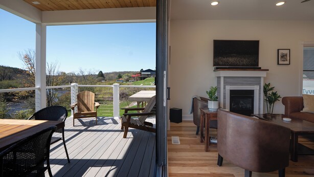 Eine Holzterrasse mit Außenmöbeln, einem Kamin und Blick auf die Landschaft.