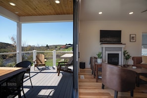 A wooden deck with outdoor seating, a fireplace, and a view of the landscape.
