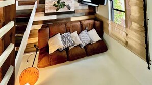 Ein gemütlicher Wohnraum mit braunem Ledersofa, einem Wand-Flachbildfernseher und Holzbodenlamellen.