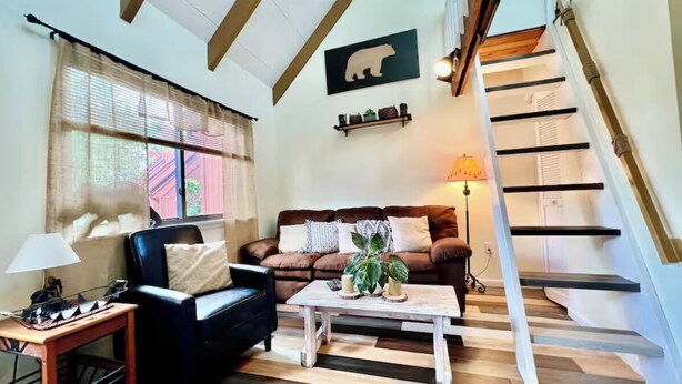 Ein gemütliches Wohnzimmer mit einem braunen Ledersofa, einem weißen Couchtisch und einer Holztreppe.