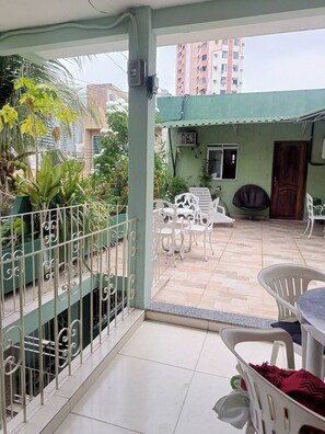 A covered outdoor patio with a tiled floor, white metal railings, and a variety of potted plants. - A house close to everything. A Place of Peace   (Campina Belém)