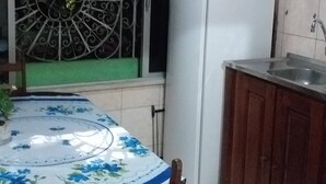 Eine Küche mit Tisch, Stühlen, einem Kühlschrank und Schränken.