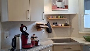 A modern kitchen with a coffee machine, kettle, and a coffee-themed poster.