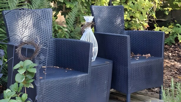 Two wicker chairs with a white lamp on a wooden deck.