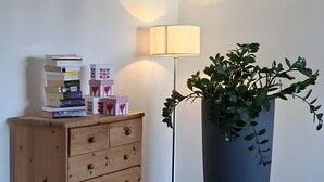 A wooden dresser with drawers, a tall floor lamp, and a large potted plant.