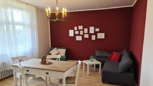 Een woonkamer met een eettafel, stoelen, een bank en een kroonluchter.