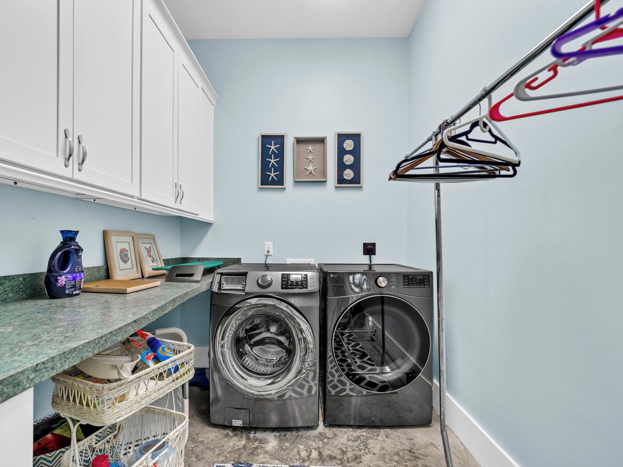 A laundry room with two front-loading washing machines, a drying rack, and a basket of laundry.