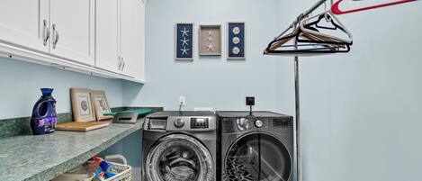A laundry room with two front-loading washing machines, a drying rack, and a basket of laundry.