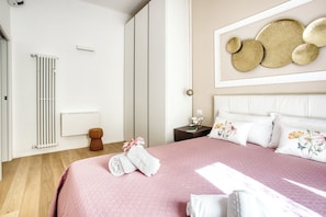 A neatly made bed with pink bedding, a white headboard, and decorative pillows. - Old Milan Navigli Family (Milan)
