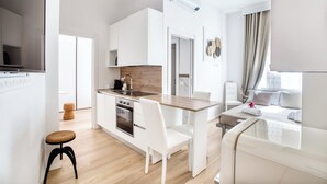 A modern kitchen with white cabinetry, a wooden countertop, and a dining area with white chairs. - Old Milan Navigli Family (Milan)