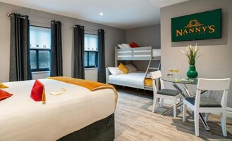 Una habitación de hotel con una cama litera, un escritorio con dos sillas, un florero con flores y un cartel enmarcado en la pared.