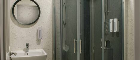 A modern bathroom with a glass-enclosed shower, a white sink, and a toilet.