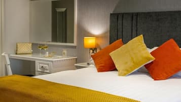 Una habitación de hotel con cama, escritorio, espejo y lámpara.