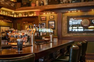 Una zona de bar con un vaso de Guinness, varios grifos y sillones de cuero.