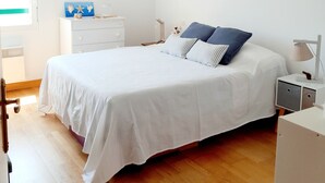 A bedroom with a large bed, a bedside table, a nightstand, a hanging light fixture, and a window. - Cosy mountain view apartment, 2 bedrooms, terrace and parking box (Hendaye)