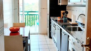 A compact kitchen with a dining area, a washing machine, and a view of the outdoors. - Cosy mountain view apartment, 2 bedrooms, terrace and parking box (Hendaye)