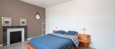 Ein Schlafzimmer mit einem Bett, Nachttischen aus Holz, einem Kamin und Wandleuchten.