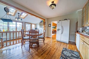 A spacious kitchen with wooden flooring, a dining area with a round table, and a large refrigerator. - Vintage Cabin w/ Views in Heart of Estes (Estes Park)