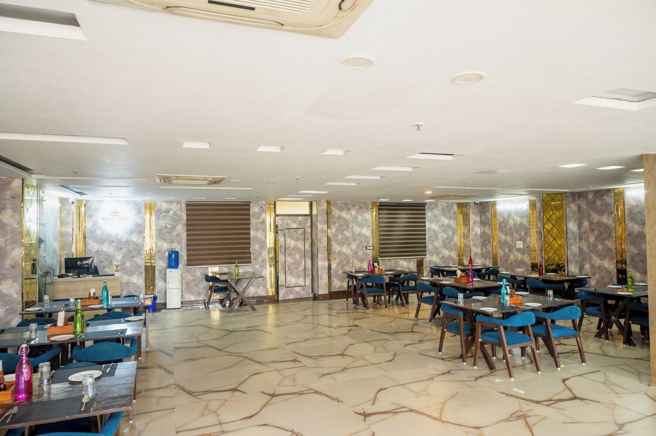 A spacious dining area with marble flooring, multiple tables and chairs, and a modern ceiling design.