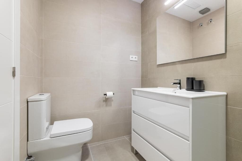 A modern bathroom with a toilet, sink, and mirror.