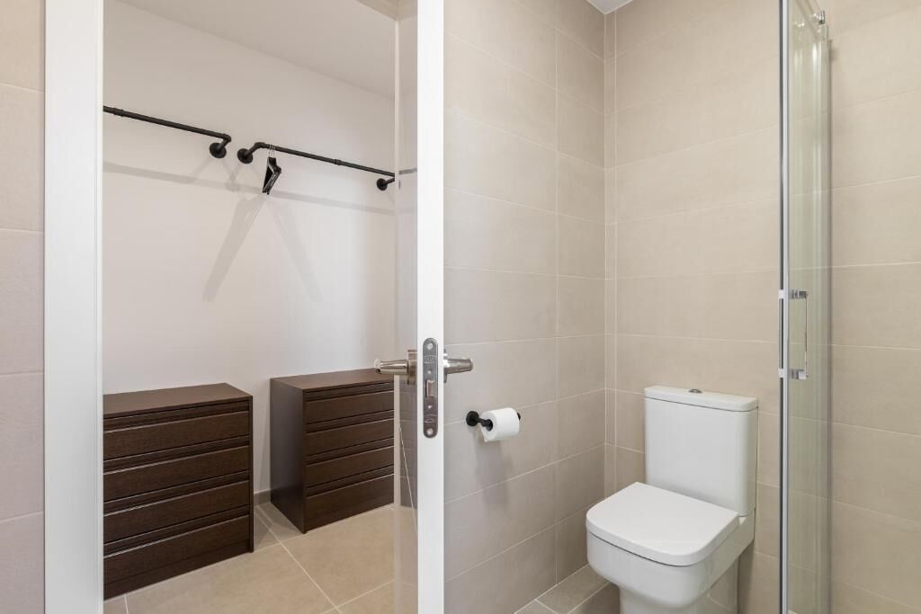 Et badeværelse med toilet, bruser og to træskabe.