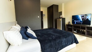 A modern bedroom with a large bed, a television, and a wardrobe. - Plume Residence Minburi (Bangkok)