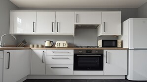 A modern kitchen with white cabinets, a built-in oven, a microwave, and a toaster. - Beautiful 1 bed flat in Wimbledon (London)