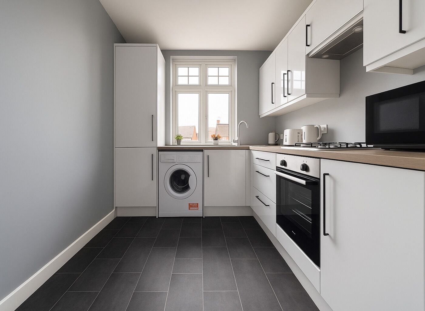 A compact kitchen with a washing machine, oven, and microwave.