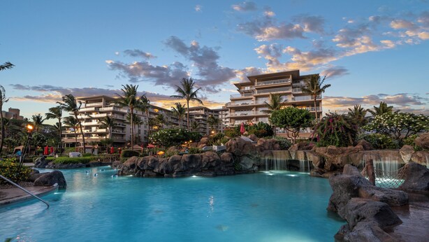 A resort with a large pool, multiple balconies, and a waterfall.