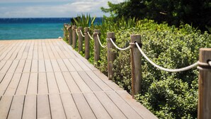 A wooden boardwalk leading to a beach with a clear view of the ocean.