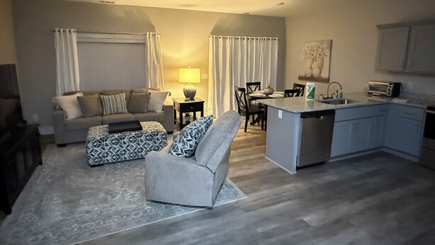 Una sala de estar moderna con sofá, reposapiés y una zona de comedor con sillas y una mesa.