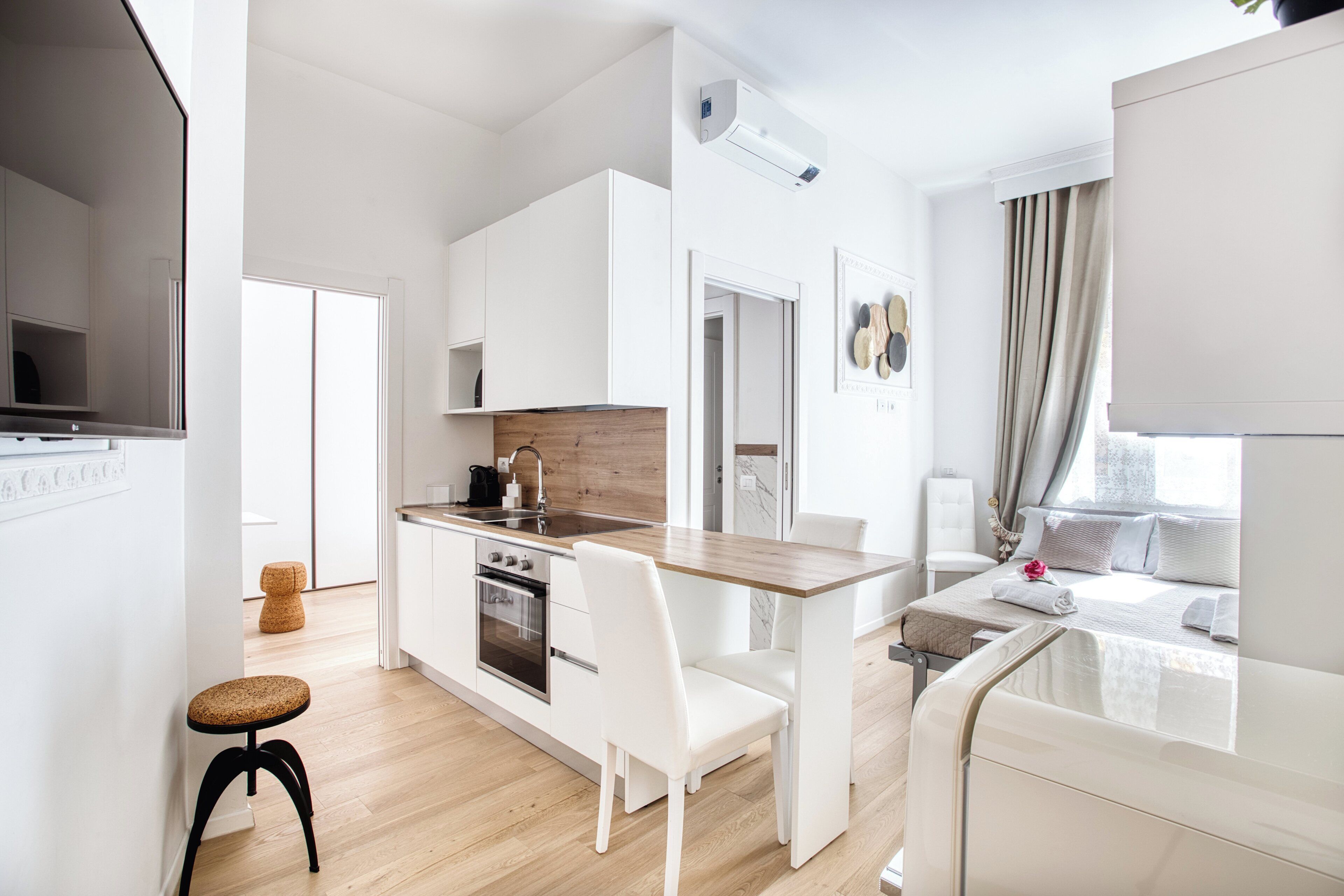 A modern kitchen with white cabinetry, a wooden countertop, and a dining area with white chairs.