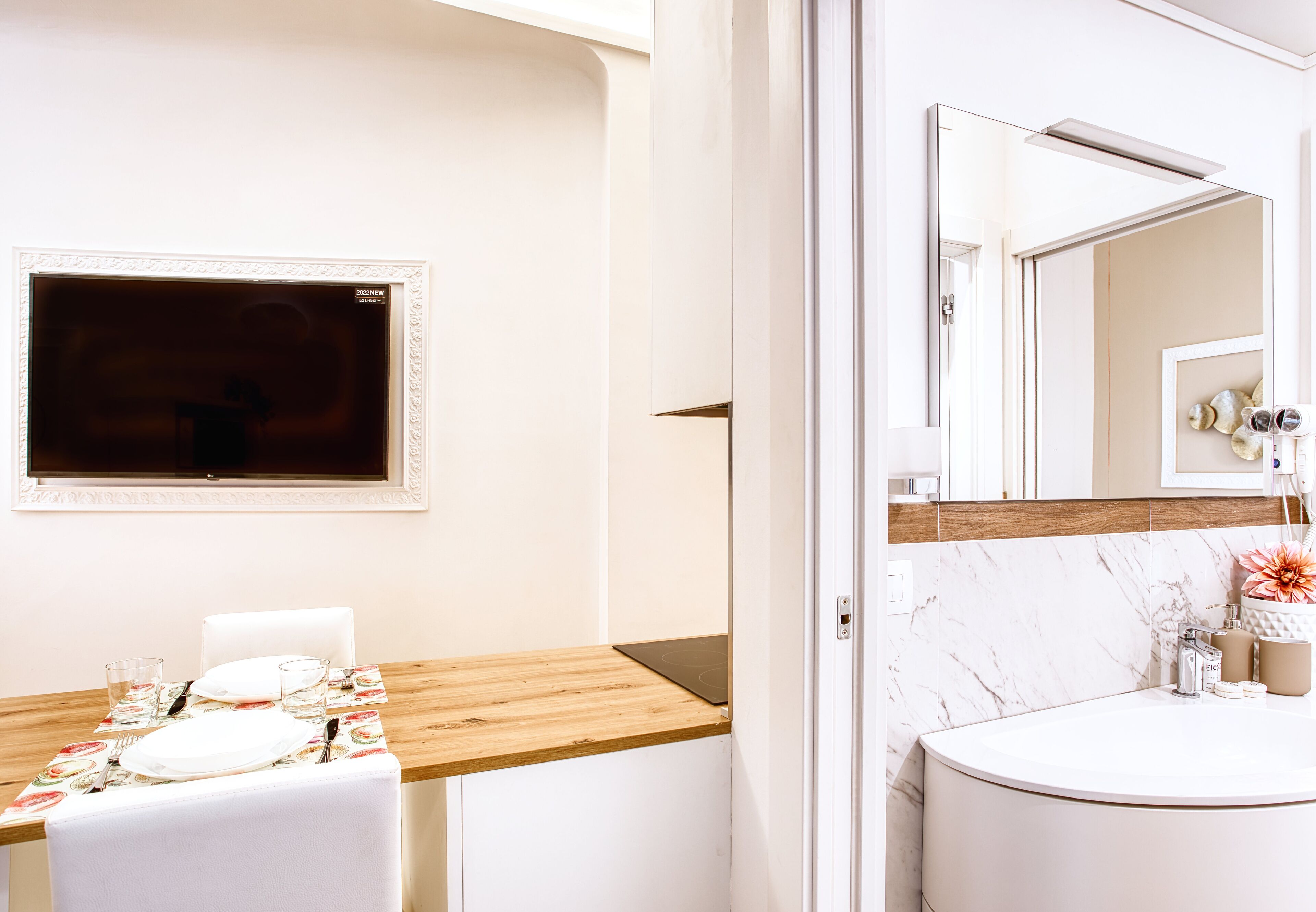 A modern bathroom with a marble sink, a wooden vanity, and a large mirror.