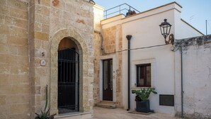 A narrow street with a stone building featuring an arched entrance and a door marked with the number 9. - Le Casine di Maruggio 9 (Maruggio)