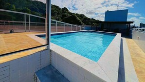 Una piscina en la azotea con vistas despejadas del paisaje circundante y un edificio moderno al fondo.