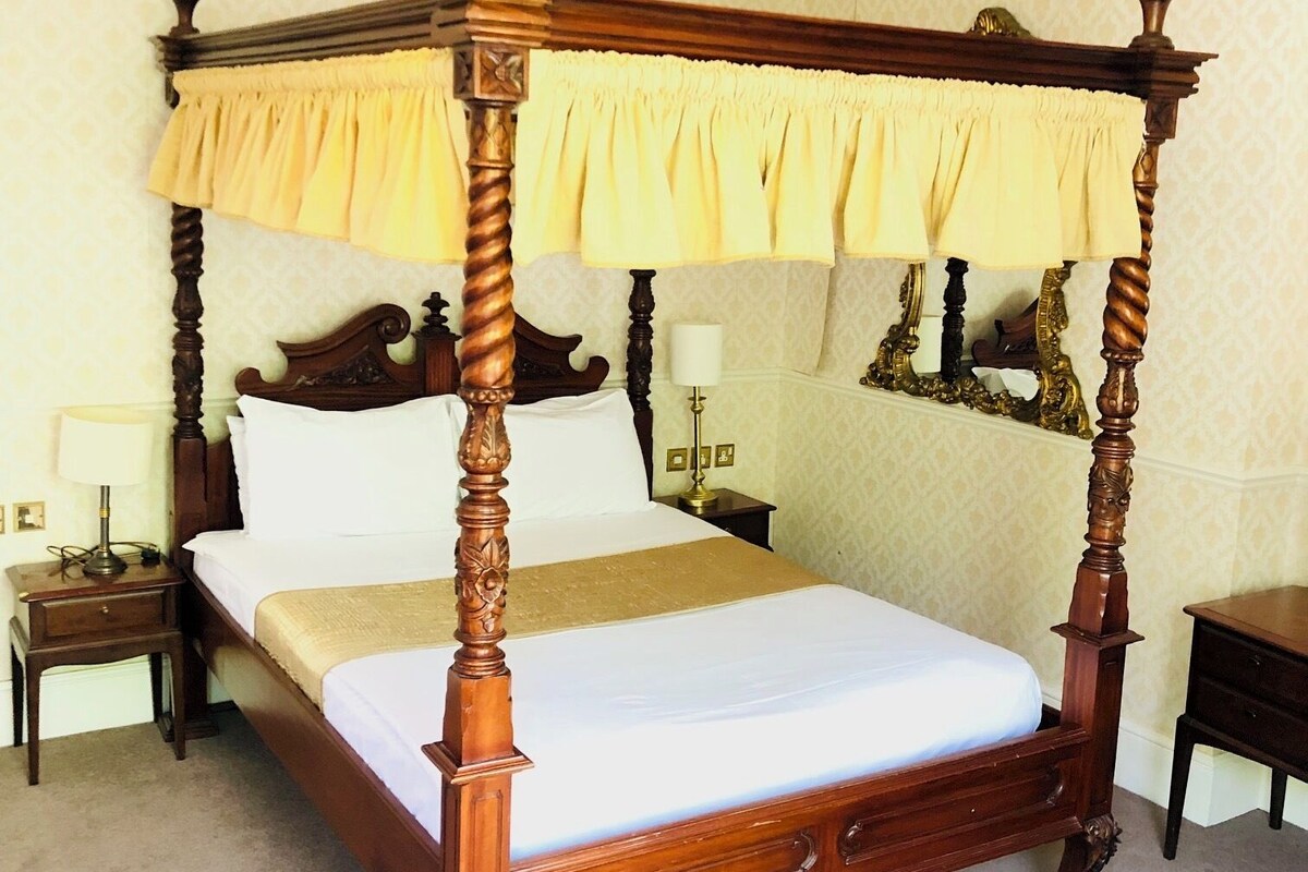 A four-poster bed with a canopy, a bedside table, and a nightstand.