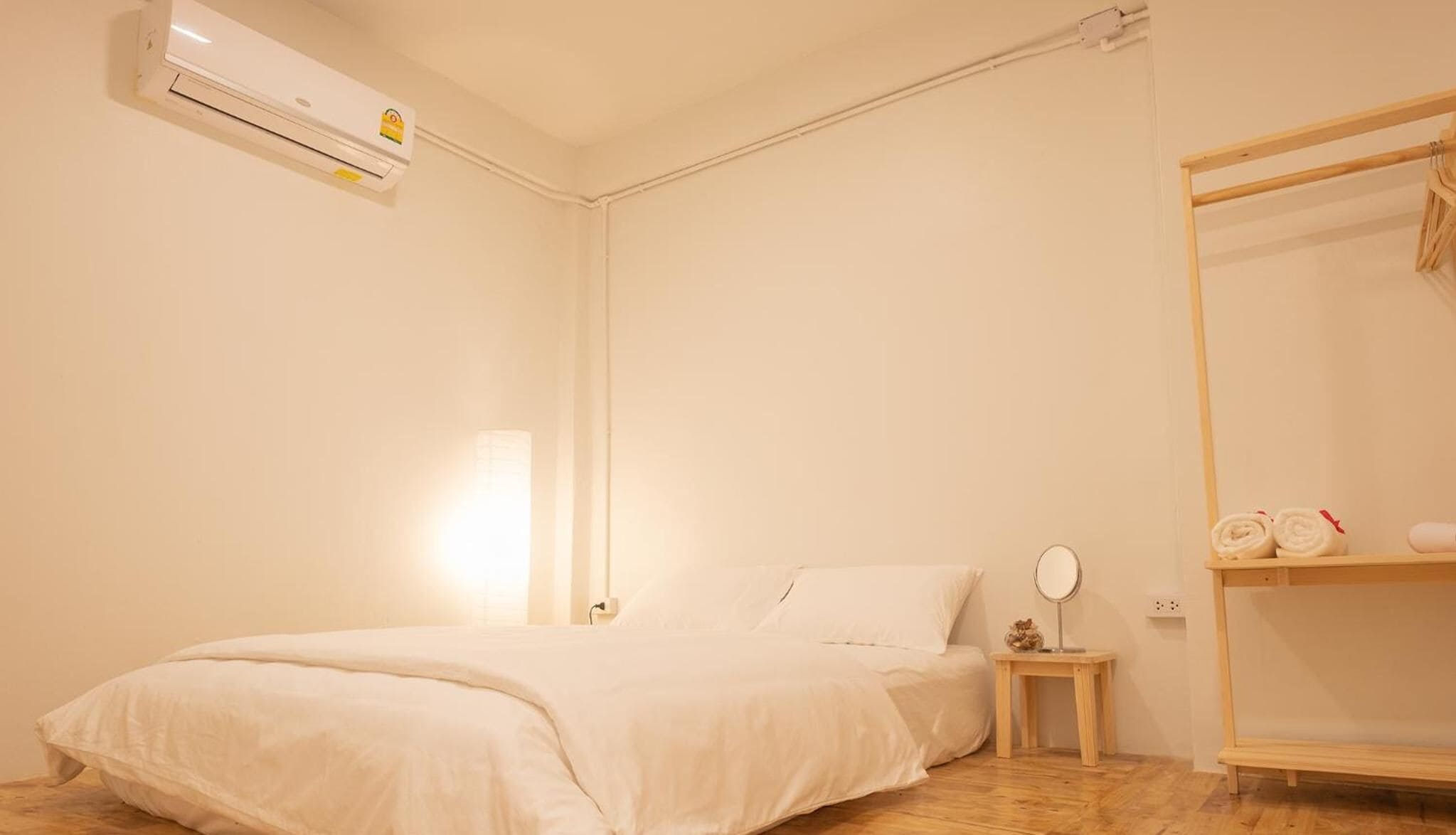 A bedroom with a bed, a bedside table with a mirror, and a wardrobe.