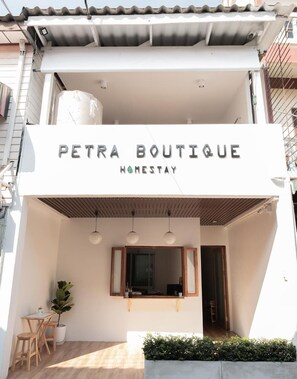Un edificio de dos pisos con un letrero que dice "PETRA BOUTIQUE HOMESTAY".
